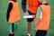 Close up of soccer coach tells the strategy of football game to his attentive teen players at stadium during training.