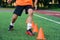 Close up soccer player`s legs running among plastic orange cones on stadium during professional training.