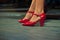 Close up of some red flamenco dance shoes on a woman`s legs on a wooden stage
