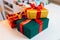 Close-up of some wrapped Christmas gift box tying red and golden ribbons, decorating beautiful bow lying on white table