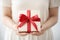 close-up of someone holding a white gift box tied with a red ribbon, christmas concept, family concept