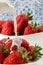 Close up. Someone pours milk cream into a plate of delicious juicy strawberries. Blue and white background