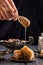 Close up. Someone`s hand is holding honey dipper and pours fragrant honey on the freshly baked oriental baklava. Turkish pottery
