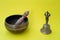 Close-up, soothing and meditative. Singing bowl with sanskrit engraving pattern and wooden mallet and golden bell of on yellow