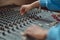 Close-up sound engineer hands using mixing board, software to create new song in professional music studio