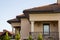 Close up of spacious brown shingle roof of modern luxurious expensive residential cottage house with three chimneys, big windows