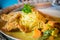 Close-up of spaghetti green curry with fried pork on table.