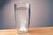 Close up sparkling water glass with dissolving effervescent aspirin pill standing on wooden table