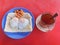 Close up a special breakfast of toast with half-put eggs and red beans with a cup tea hot drink water on red background