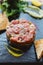 Close up Spicy Bluefin Tuna Tartare with sour and spicy sauce. Served with toast and salad on black stone plate