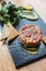 Close up Spicy Bluefin Tuna Tartare with sour and spicy sauce. Served with toast and salad on black stone plate