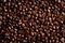 Close-up on spilled beans of quality roasted coffee, top view. Background with many coffee beans