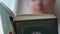 Close-up of the spine, cover of a thick art book, reads a girl in the background