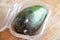 Close-up spoiled avocado in plastic box on wooden background