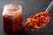 Close up of spoon of chilli sauce with bottle on background