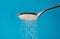 Close up of spoon pouring granulated refine white sugar