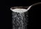 Close up of spoon pouring granulated refine white sugar