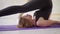 Close-up sporty blonde woman in black sportswear practicing yoga in white yoga studio.