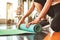 Close up of sporty woman folding yoga mattress in sport fitness gym training center background. Exercise mat rolling keeping after