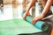 Close up of sporty woman folding yoga mattress in sport fitness gym training center background. Exercise mat rolling keeping after