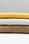 Close up of stack of beige, brown, mustard knitted pullovers, side view. Simple minimal cozy clothes concept