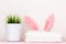 A close-up of a stack of clean white bedding, Easter bunny ears and a houseplant, on a dressing table