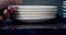 Close-up of a stack of empty white plates in the kitchen. Male hands taking dishes.