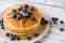 Close up of a stack of fluffy pancakes with maple syrup poured over them.