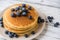 Close up of a stack of fluffy pancakes with maple syrup poured over them.