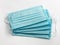 Close up stack light blue face protective surgical mask for protective coronavirus COVID-19 pandemic dust particles on white