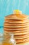 Close up of stack of pancake with honey, butter and jar of honey