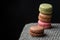 Close-up of stacked macarons, with selective focus, on gray knitted blanket and black background, horizontally,