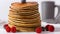 Close-up of stacked pancakes, blueberries and raspberries, isolated on white background