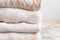 Close up of stacked wool knitted sweaters or jumpers, in white and light tones, cozy image, soft fabrics in white background