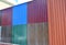 Close up on stacks of various colorful metal fence panels and metal roof sheets for sale.