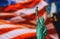 CLOSE UP OF STATUE OF LIBERTY WITH BLUR AMERICAN FLAG