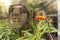 Close-up on a statue of a Moai head surrounded by tropical flowers at the west exit of Shibuya Station in Tokyo, Japan.