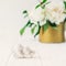 Close up statuette of two antique little lovely angels of the gypsum on the white wooden table with bouquet of white peonies in vi