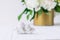 Close up statuette of two antique little lovely angels of the gypsum on the white wooden table with bouquet of white peonies in vi