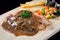 Close up steak pork with mushroom sauce, french fries and salad