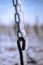 Close up of a steel chain in the vineyard covered in frozen rain in bright sunshine.