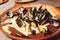 Close Up Still Life of Oysters with Cheesy Gratin Topping Served on Plate with Green Garnish on Painted Wooden Table