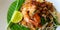 Close up stir fried with rice noodle, river prawn or shrimp, bean sprout, sliced chives and lime on banana leaf.