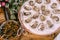 Close-up of stitches in a plate on a table with kitchen tongs and a ladle of stuffed olives on a wooden table.