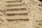 Close-up of stone stairs and sand on the Mediterranean beach, background footprints in the sand