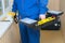 Close-up, storage for tools in the hands of a worker in a blue special suit and a yellow stapler