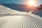 Close-up straight line rows of freshly prepared groomed ski slope piste with bright shining sun and clear blue sky background.