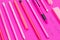 Close up of straightly arranged group of pink color writing equipment on pink surface isolated