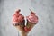 Close up strawberry ice cream and waffle cone decorated with white sesame, black sesame and fresh strawberry in glass on ground on