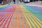 Close up of streaks of color on concrete road with rainbow crosswalk and low view of cars